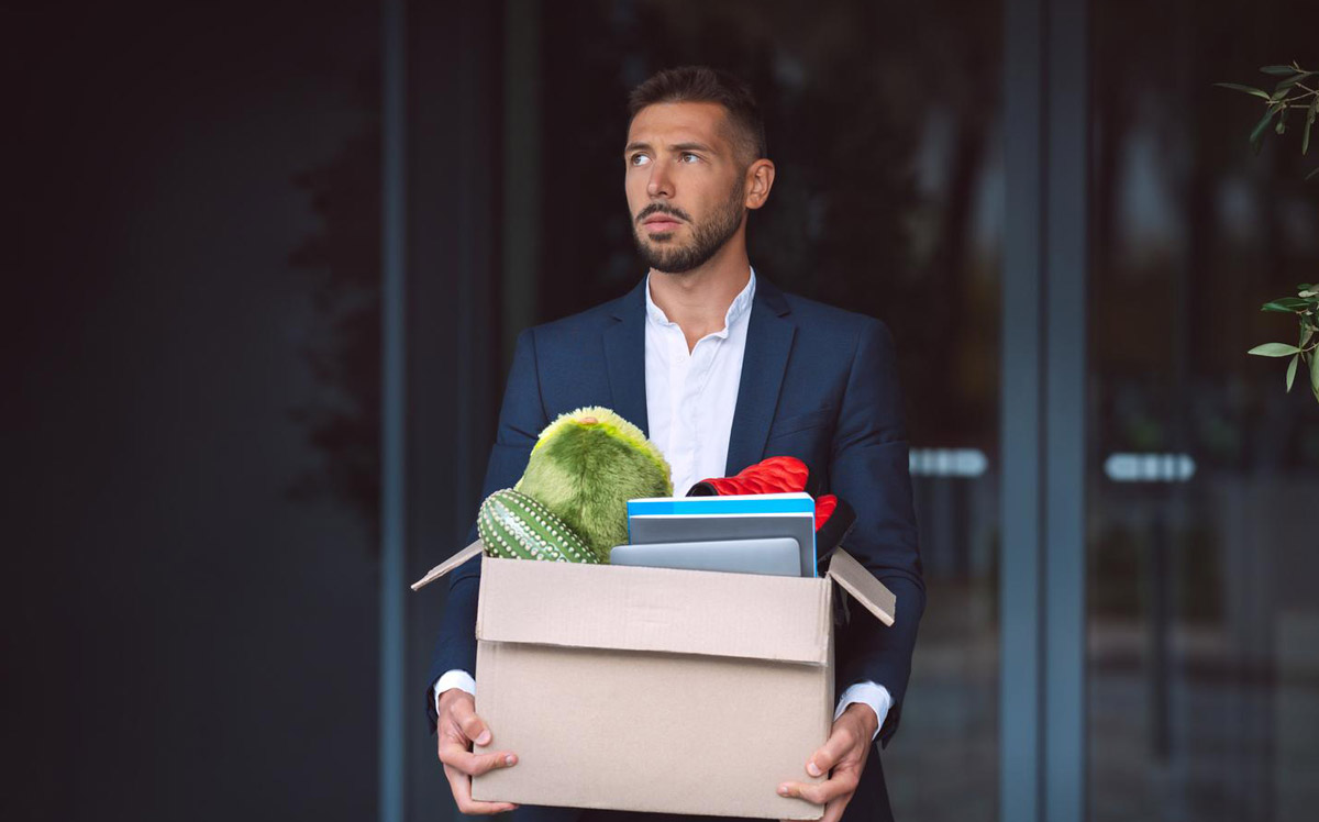 Un homme en costume avec un carton à la main, qui vient d'être licencié